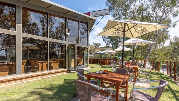 An outdoor dining area with tables and chairs, umbrellas, and a view of the surrounding landscape. - Mannum Motel (Mannum)