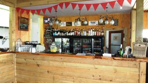 A bar area with wooden walls, a red carpet, and a variety of bottles and glasses on shelves. - Fat Owl Motel, Bar & Eatery (Piopio)