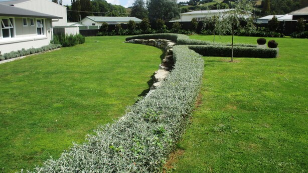 A well-maintained lawn with a stone pathway leading to a building. - Fat Owl Motel, Bar & Eatery (Piopio)