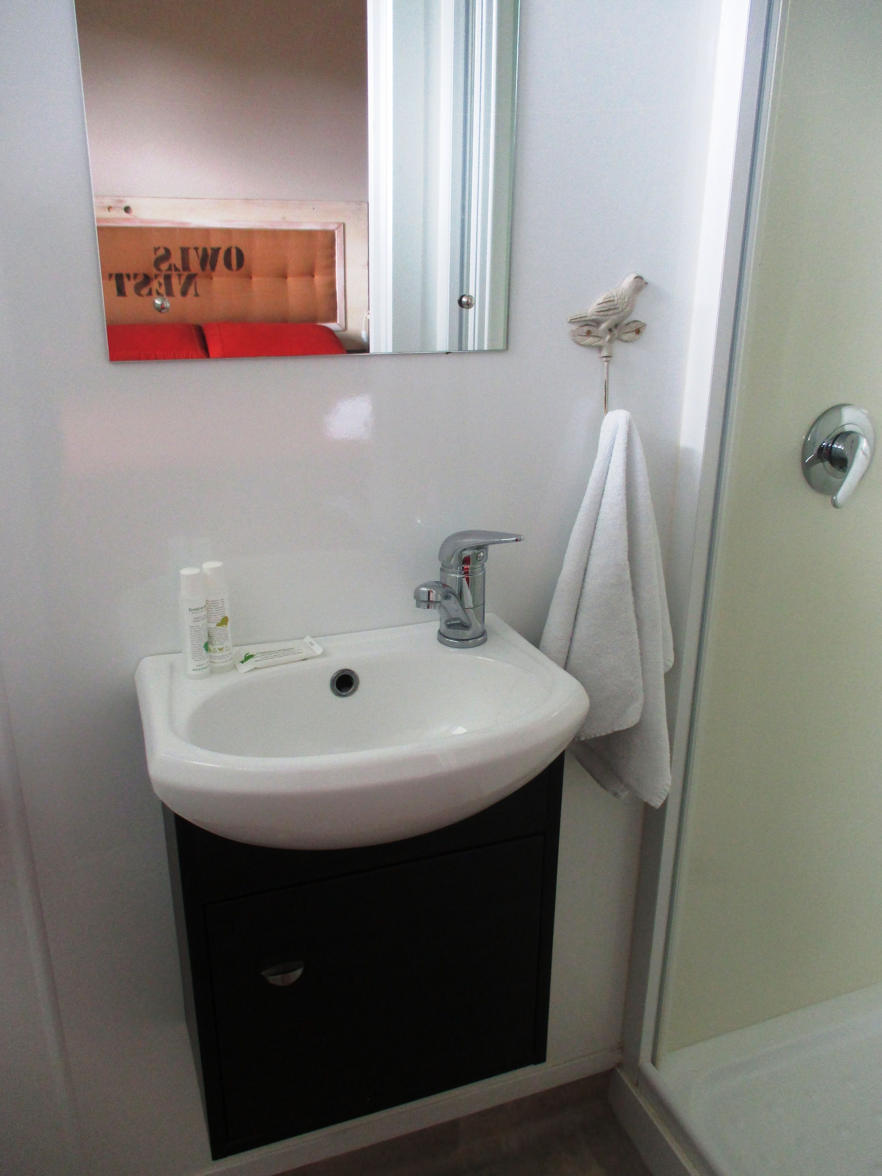 A bathroom with a white sink, a mirror, and a towel hanging on the wall.