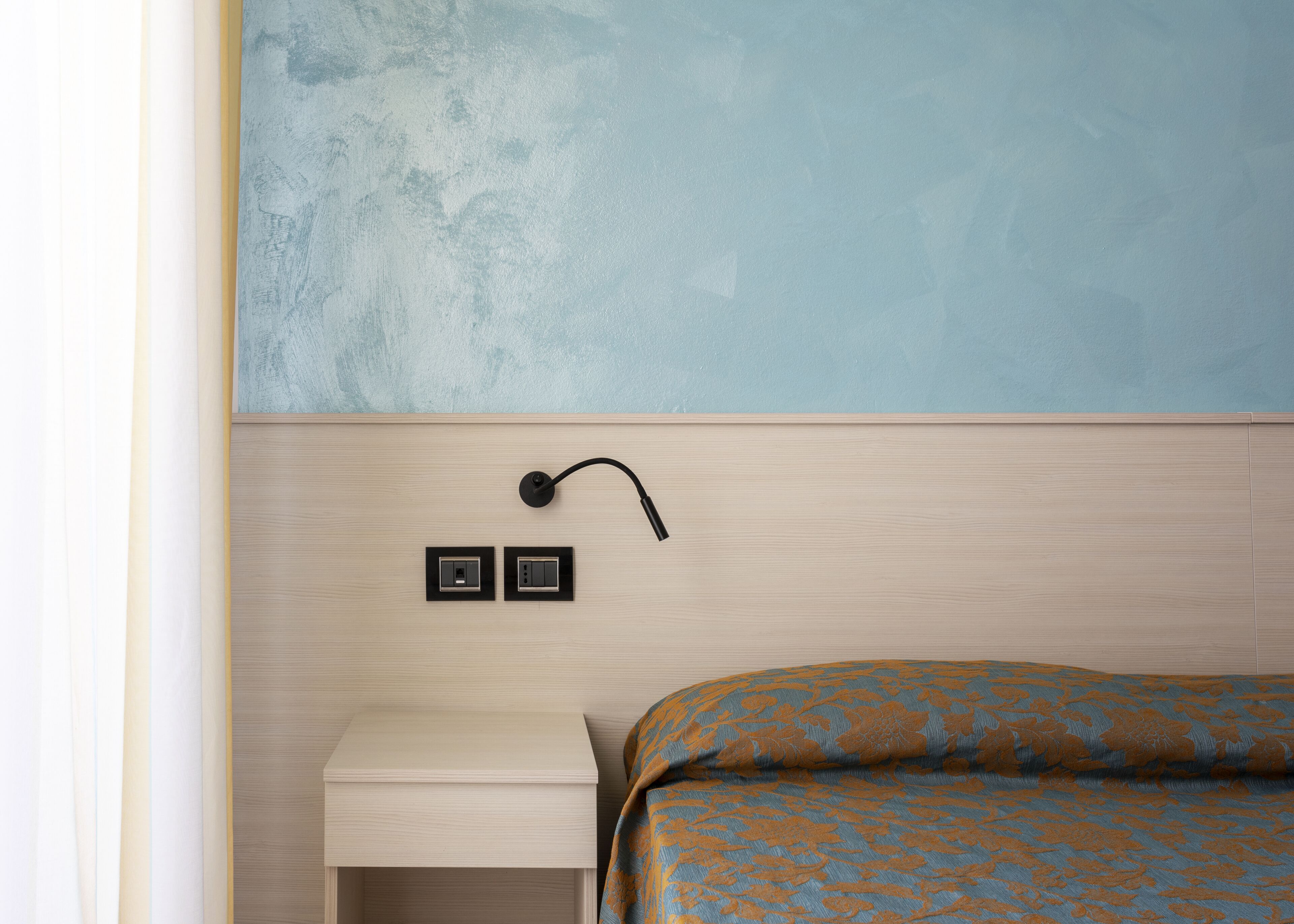 A bedroom with a wooden headboard, a bedside table, and a patterned bedspread.