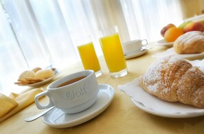A breakfast setting with a croissant, a glass of orange juice, and a cup of coffee on a table. - Hotel Golf (San Michele al Tagliamento)
