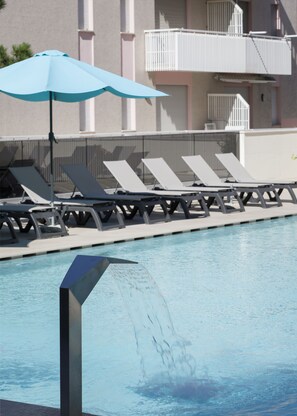 A swimming pool with lounge chairs and a blue umbrella. - Hotel Golf (San Michele al Tagliamento)