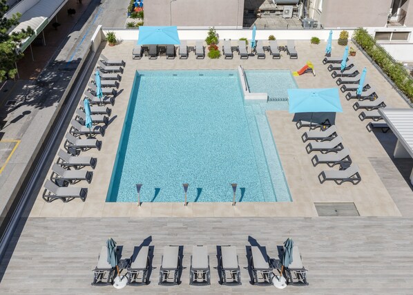A rooftop swimming pool with sun loungers and umbrellas, surrounded by a tiled deck. - Hotel Golf (San Michele al Tagliamento)