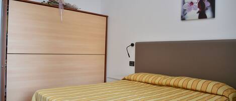 Un dormitorio con una cama, un armario de madera y un cuadro de flores colgado en la pared.