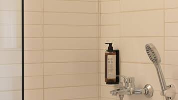 A shower with a handheld showerhead and a bottle of shampoo.