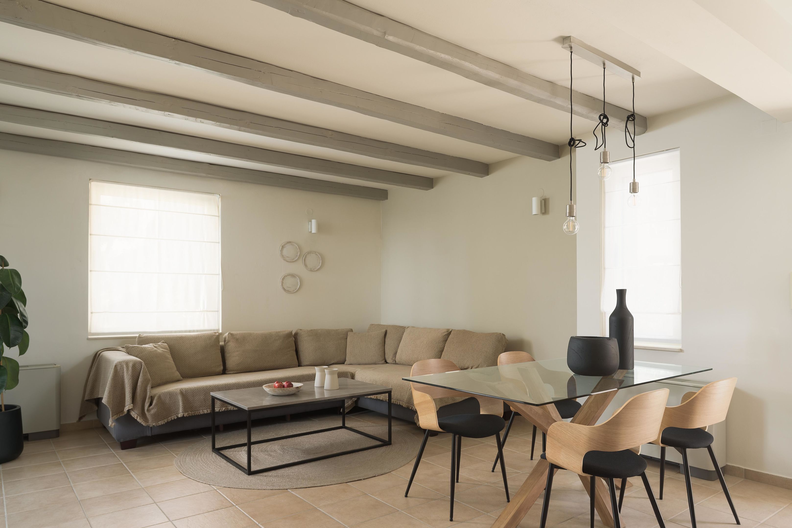 Una sala de estar moderna con una mesa de centro de vidrio, un sofá color beige y un comedor con sillas.