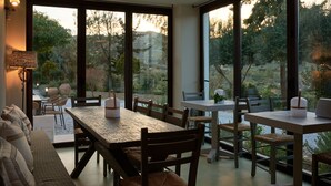 A dining area with a large table and chairs, large windows with a view of trees and a mountain.