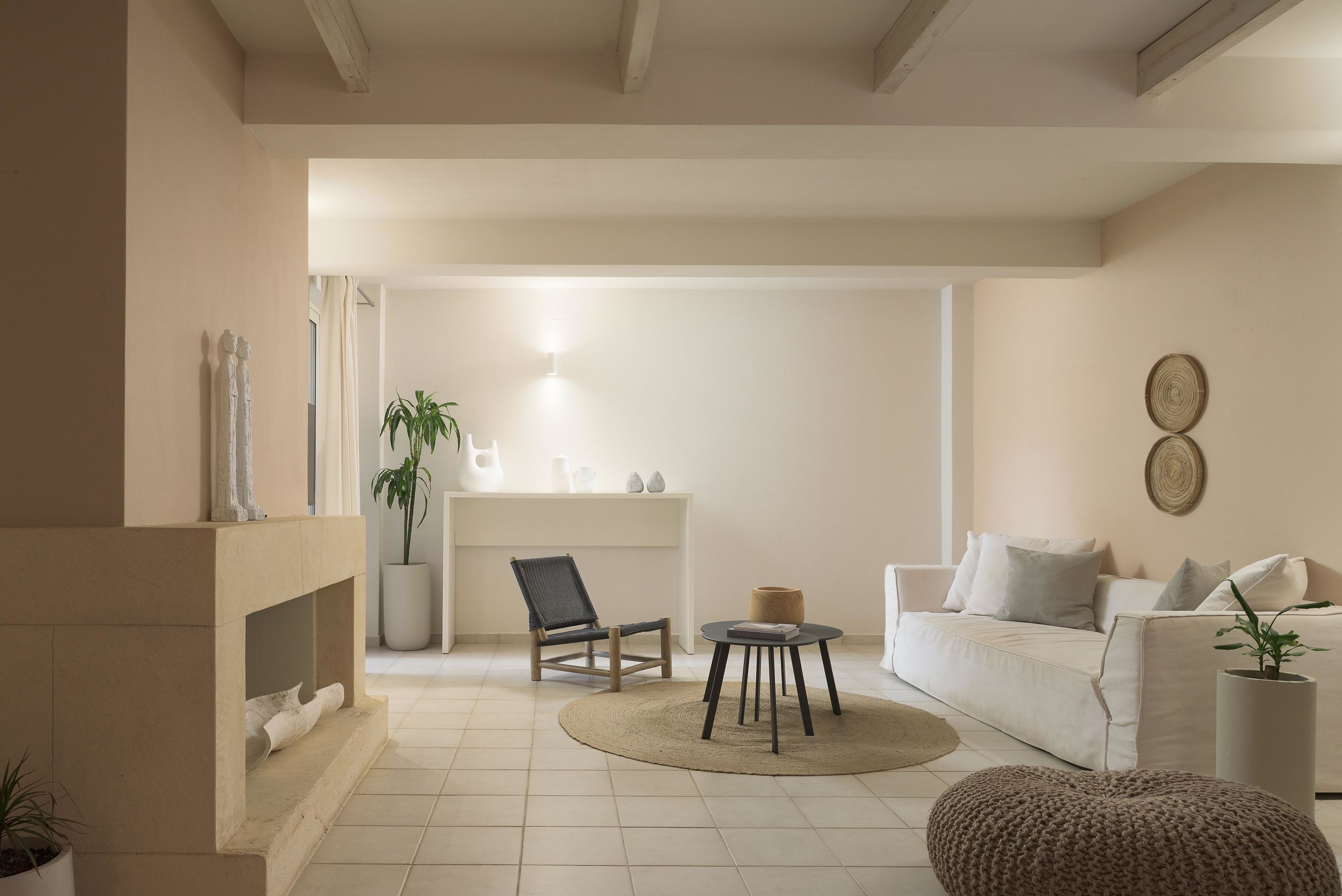 Una sala de estar con chimenea, un sofá, una silla, una mesita y una planta en maceta.