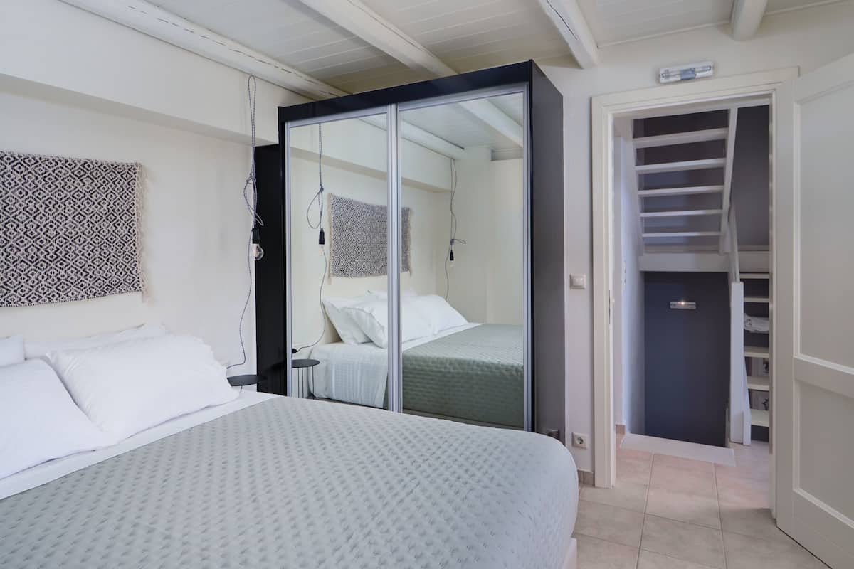 A bedroom with a bed, a wardrobe, and a mirror.