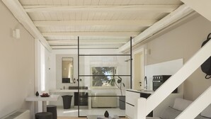 A modern kitchen with a central island, a dining area with a table and chairs, and a staircase leading to another level.