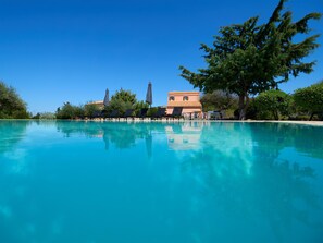 Alberca al aire libre, sombrillas en la alberca y camastros