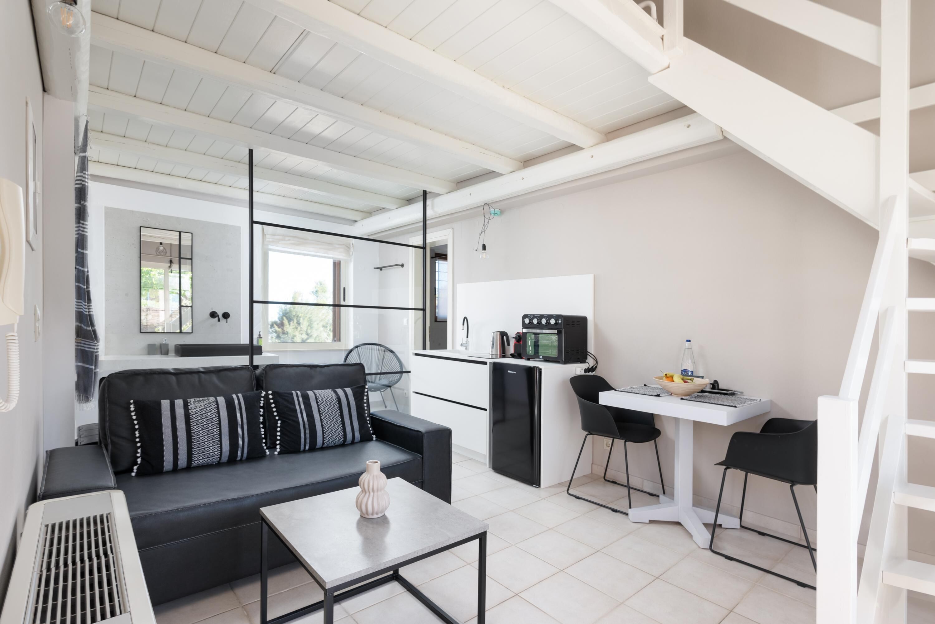 A compact living space with a sofa, a small table, a kitchenette, and a dining area.