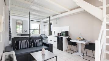 A compact living space with a sofa, a small table, a kitchenette, and a dining area.