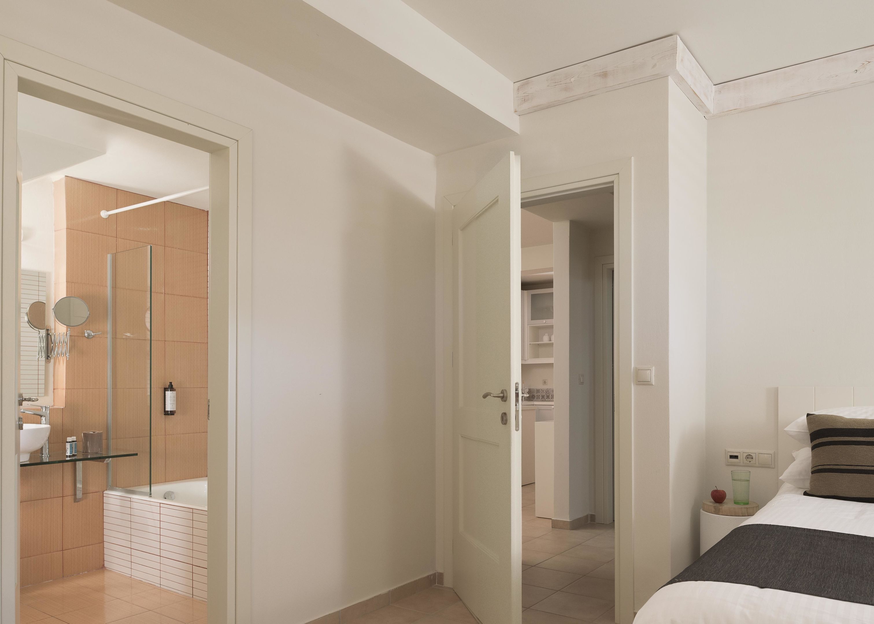 Habitación de hotel con cama, mesita de noche con lámpara, armario y baño con ducha e inodoro.