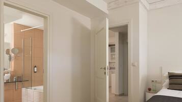Habitación de hotel con cama, mesita de noche con lámpara, armario y baño con ducha e inodoro.