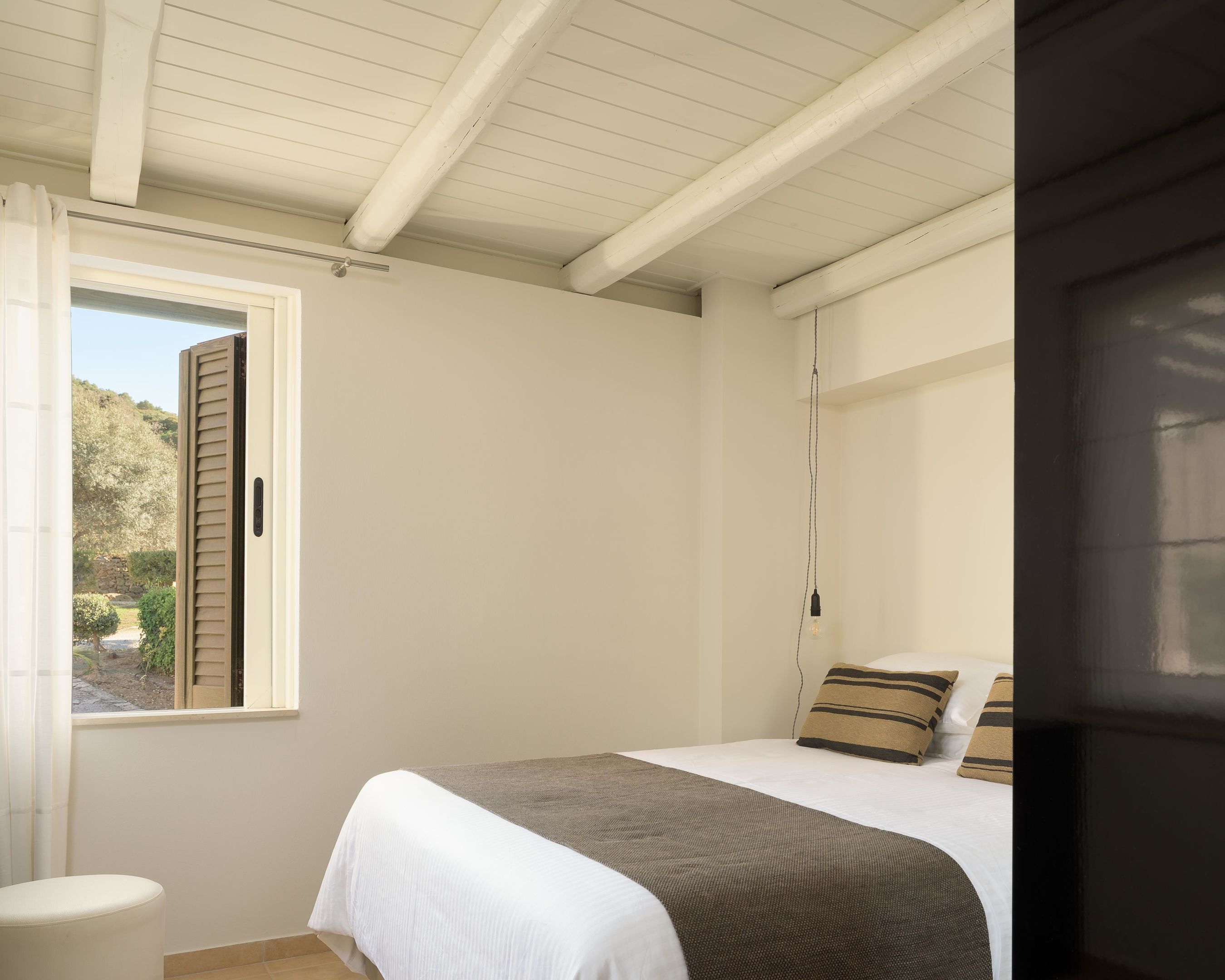 A bedroom with a bed, a window, a door, and a view of the outdoors.