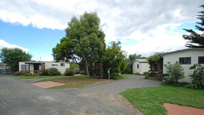 A campground with two mobile homes, a paved driveway, and a grassy area with trees. - Triabunna Cabin and Caravan Park (Triabunna)