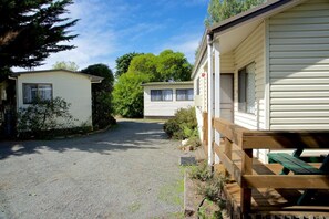 A gravel driveway leading to a row of mobile homes with a wooden deck and picnic table. - Triabunna Cabin and Caravan Park (Triabunna)