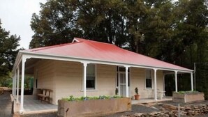 A single-story house with a red roof and a covered porch. There are potted plants on the porch and a stone wall in front. - Brown's House Bed and Breakfast (Boconnoc Park)
