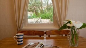 A wooden table with a magazine, a striped mug, and a vase with white flowers. - Brown's House Bed and Breakfast (Boconnoc Park)