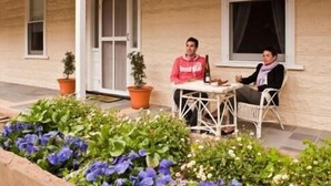 A two-person outdoor seating area with a table and chairs, surrounded by potted plants and flowers. - Brown's House Bed and Breakfast (Boconnoc Park)