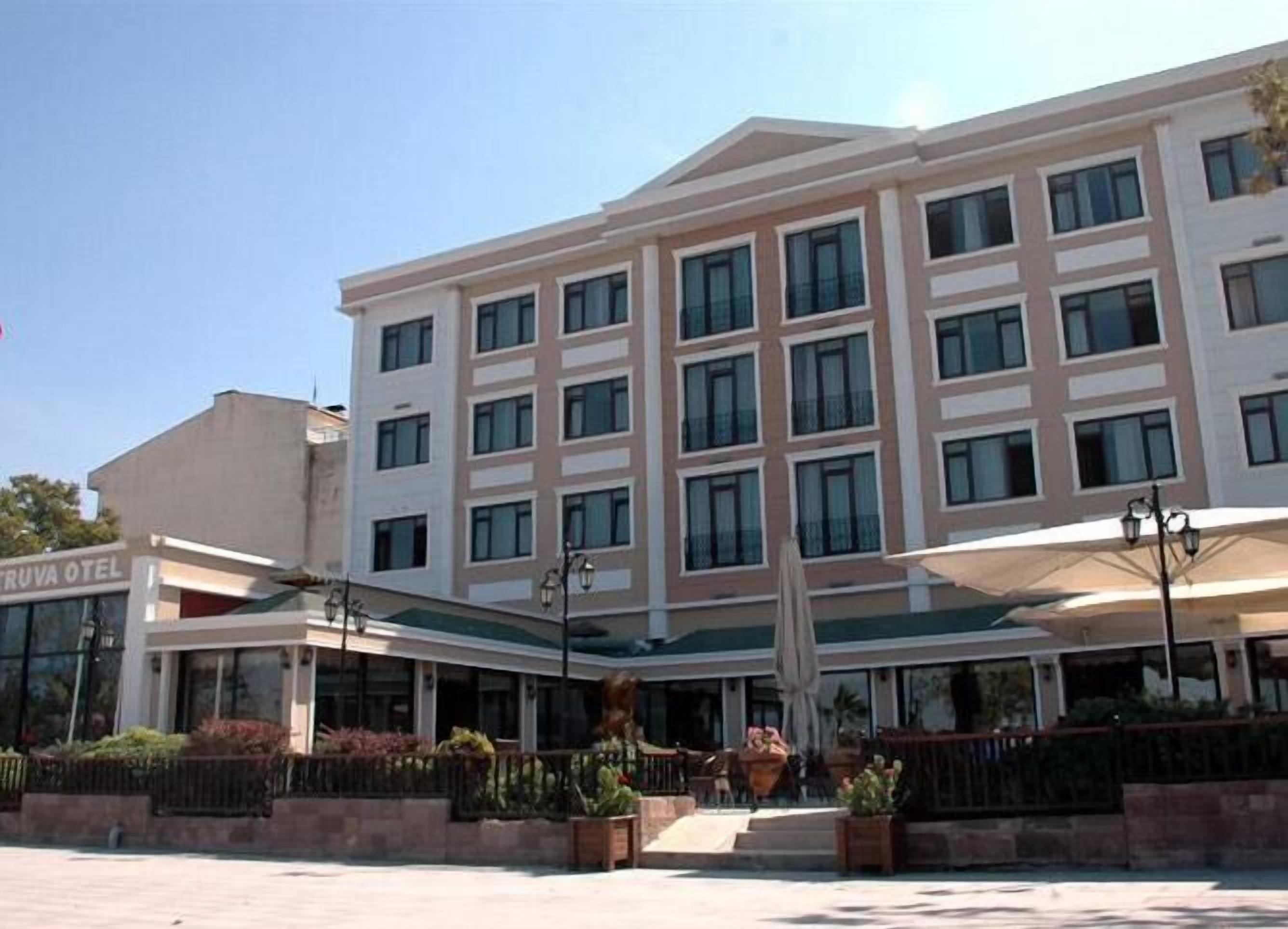 A multi-story hotel with a flat facade, large windows, and a covered entrance area with outdoor seating.