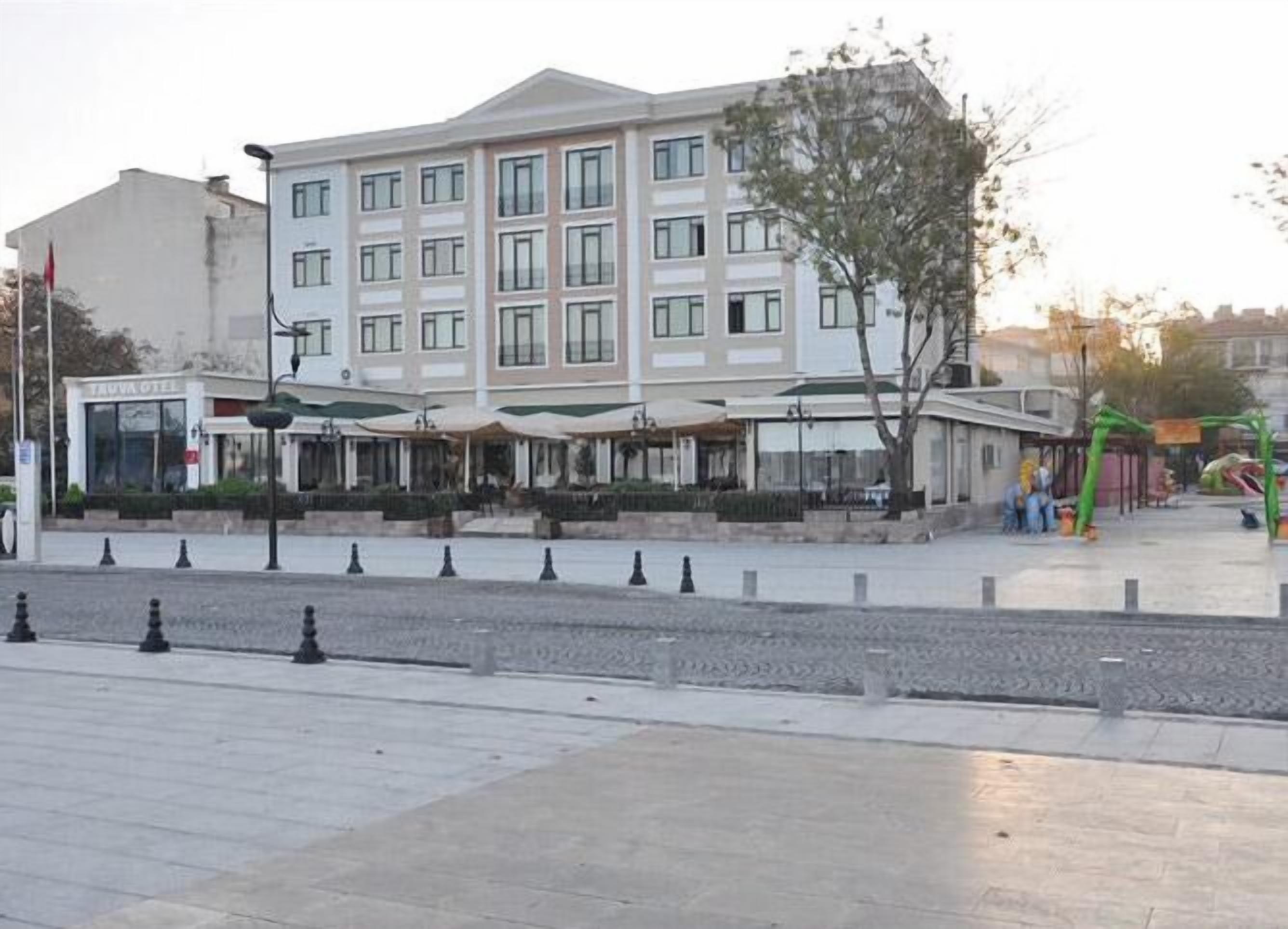 A multi-story hotel with a central courtyard, outdoor seating area, and a flagpole.