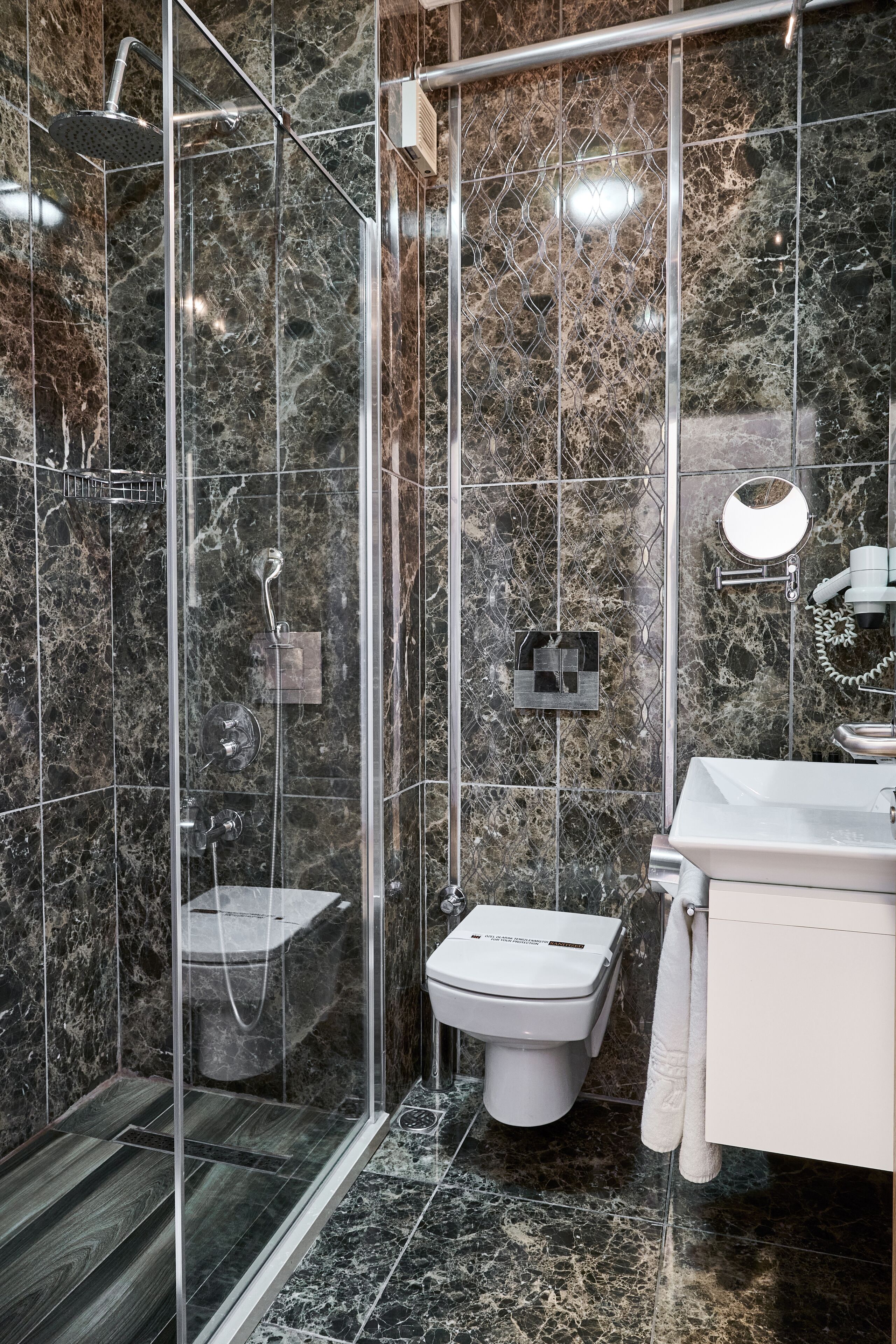 Un baño moderno con ducha de vidrio, inodoro y lavamanos con espejo.