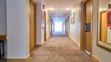 Un pasillo largo y estrecho con pisos alfombrados y puertas de madera a ambos lados.