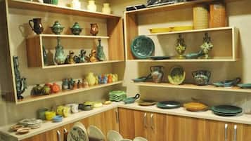 A kitchen with wooden cabinets and shelves displaying various ceramic dishes and utensils.