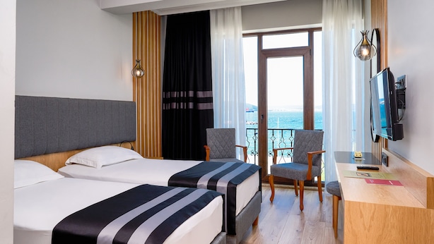 Habitació d'hotel amb dos llits, una taula de treball, una cadira i una televisió.