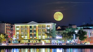Hotel amb una gran lluna il·luminada al fons, reflectida en una massa d'aigua.