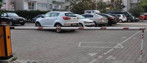 A parking area with multiple cars parked in front of residential buildings.