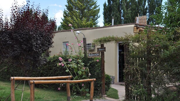 A rustic building with a wooden bench in front, surrounded by greenery and a sign that reads "La Casa de Jefe". - La Casa de Feli (Barreal)