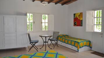Quarto com cama, mesa e cadeiras, guarda-roupa e um quadro na parede.