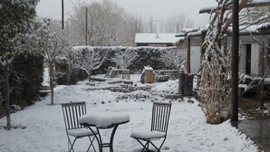 A snow-covered outdoor area with two metal chairs and a small table. - La Casa de Feli (Barreal)