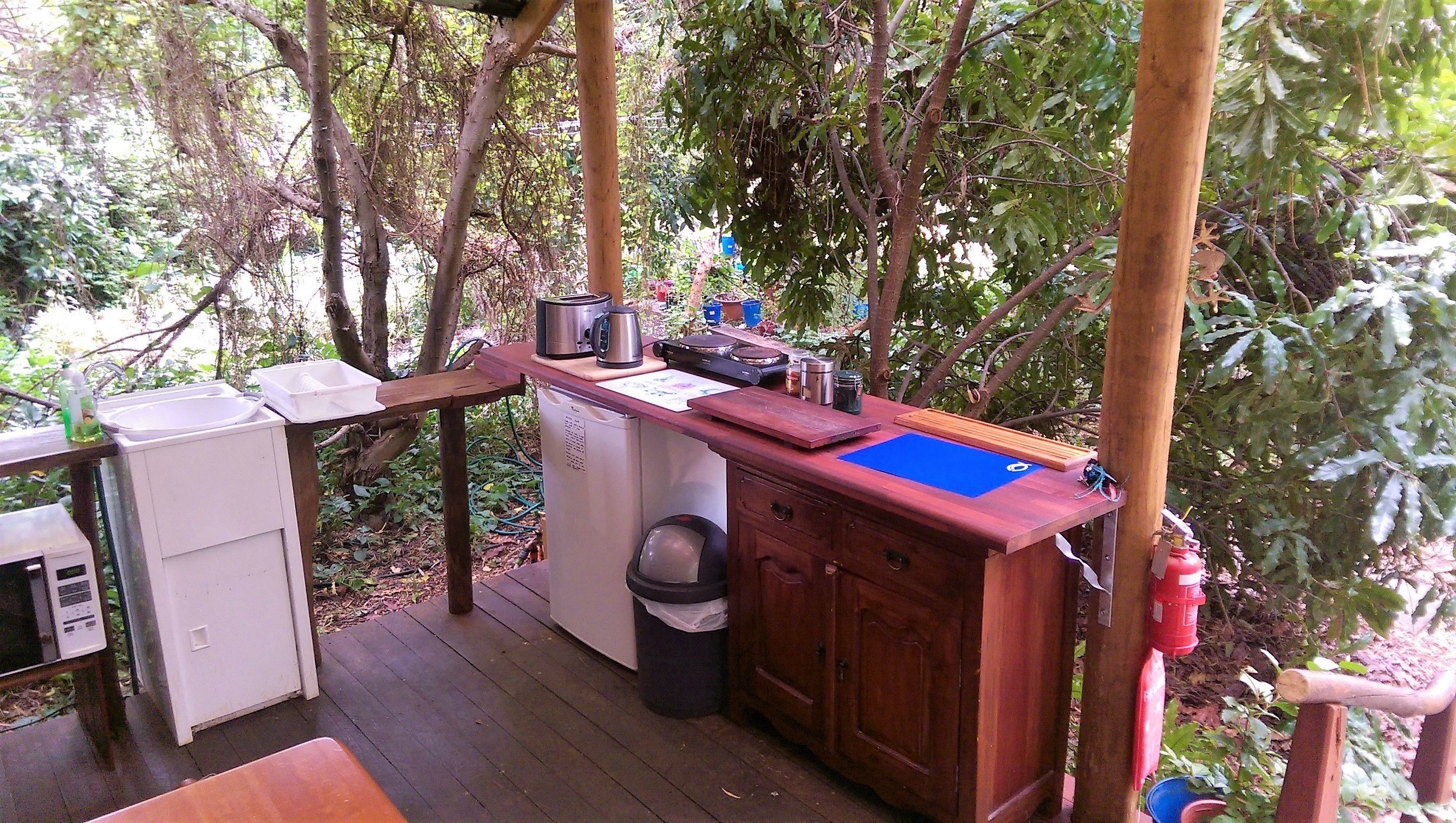 Une terrasse en bois équipée d’un évier, d’un petit réfrigérateur et d’une poubelle.