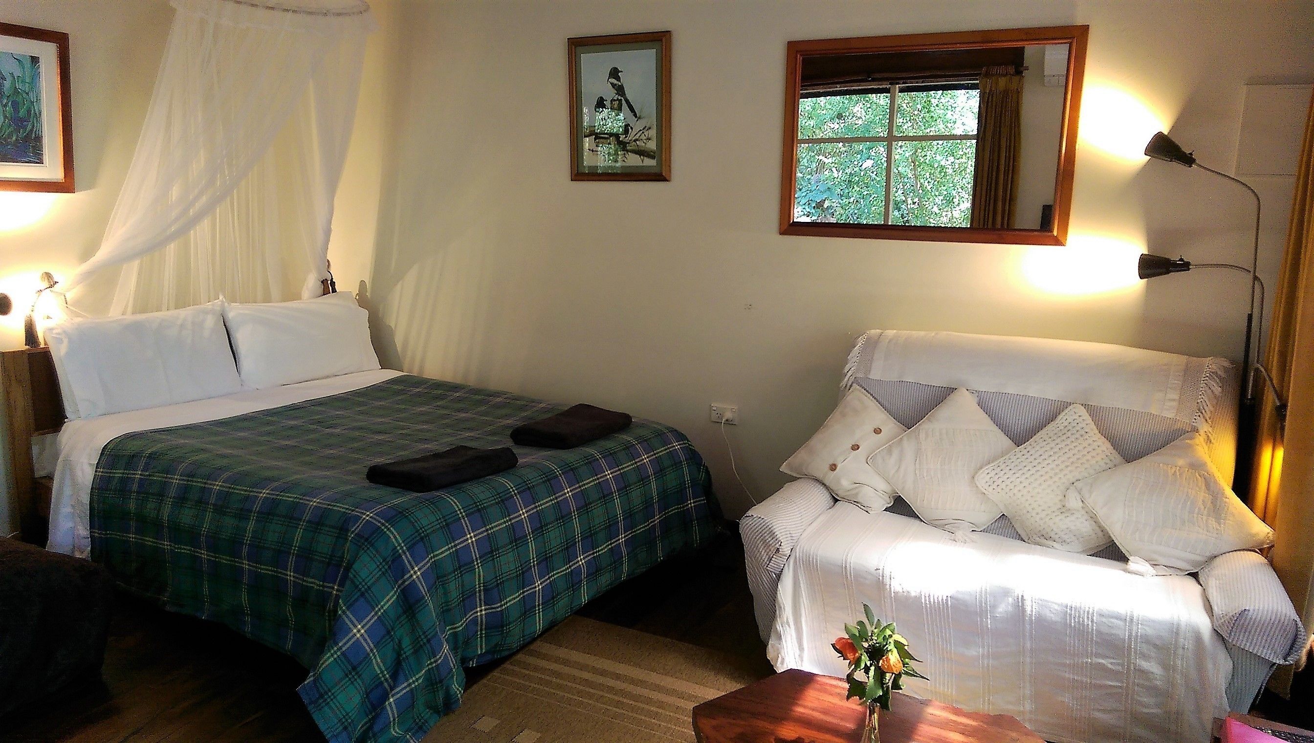 A bedroom with a bed, a chair, a window, and a bedside lamp.
