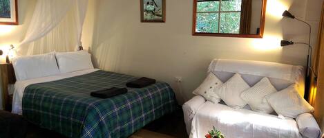 A bedroom with a bed, a chair, a window, and a bedside lamp.