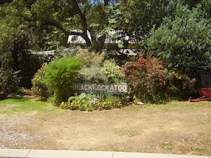A sign for Blackcockatoo with a garden path leading to it, surrounded by various plants and trees. - The Black Cockatoo Nannup (Nannup)