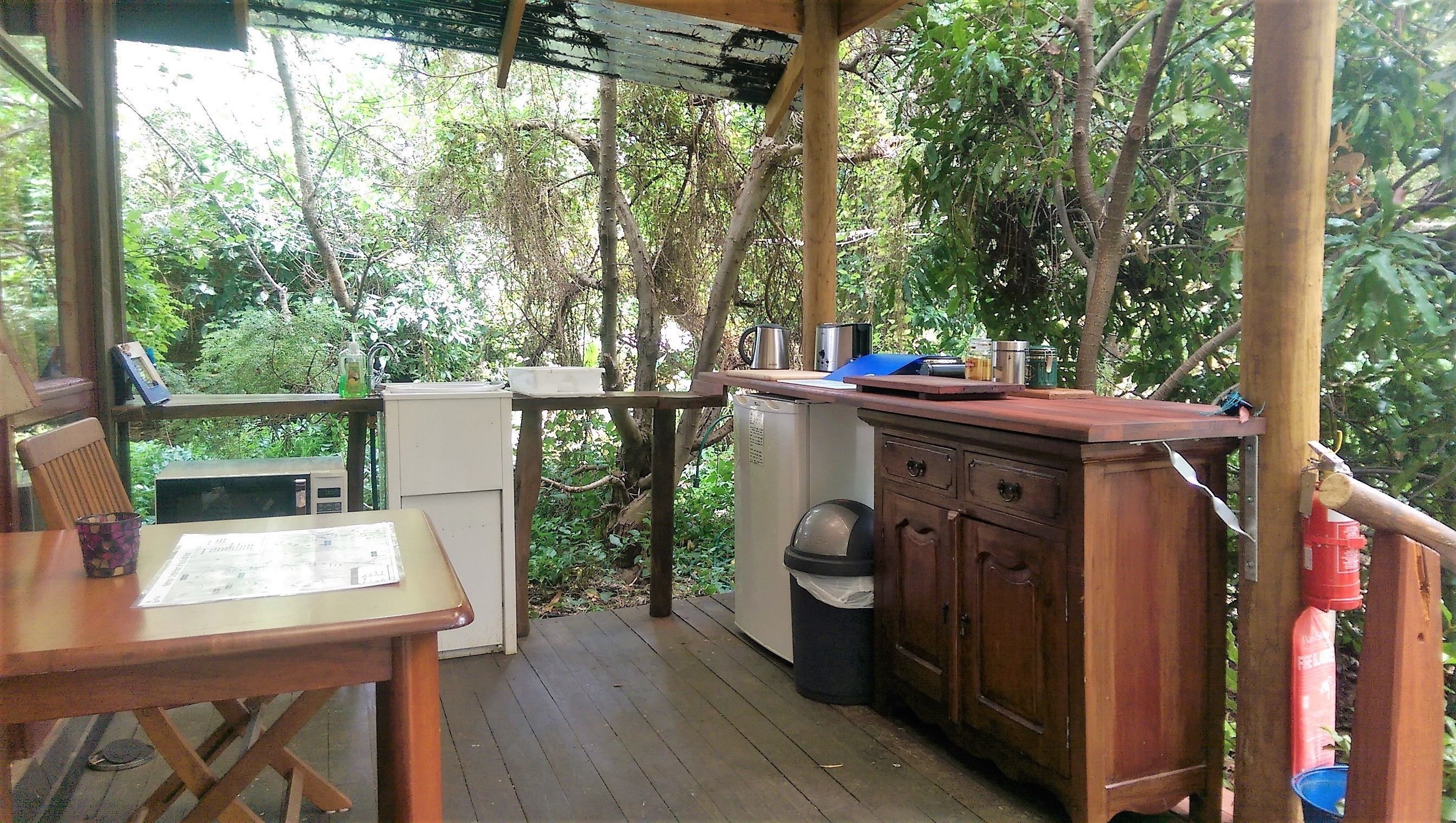 Eine Holzterrasse mit Tisch, einem kleinen Kühlschrank und einem Schrank.