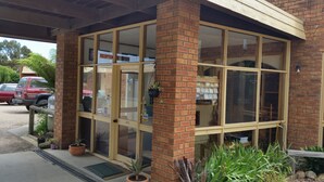 Una zona de recepción con puerta de cristal, paredes de ladrillo y plantas en macetas.