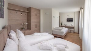 Ein Hotelzimmer mit zwei Betten, einem Fernseher, einem Schreibtisch und einem Kleiderschrank.