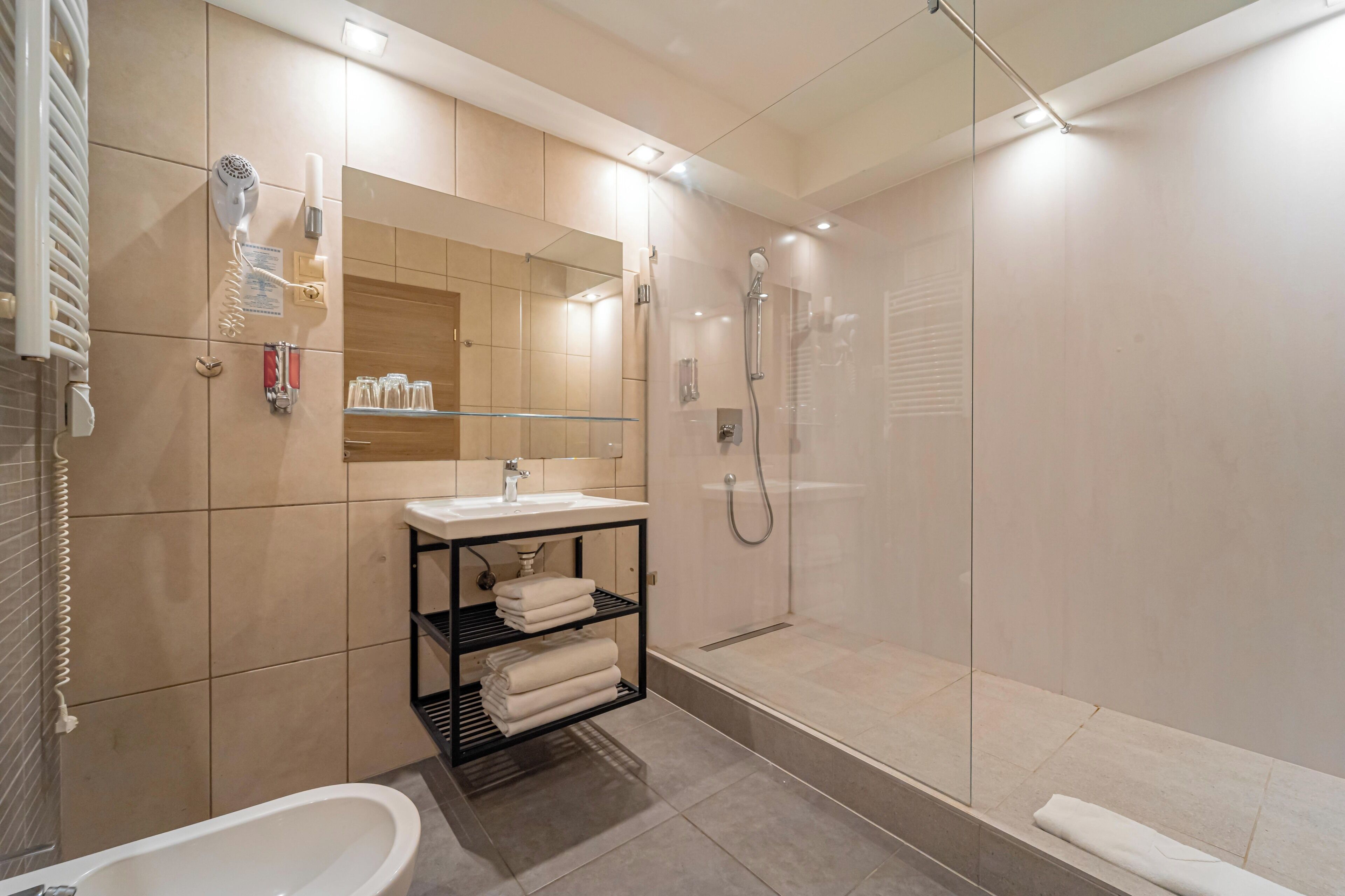 Un baño moderno con bañera, lavamanos, ducha con mampara de vidrio y tocador con espejo.