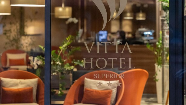 Ein Hotel-Empfangsbereich mit modernem Design, mit orangefarbenen Sesseln und einem Empfangstresen.