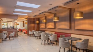 Ein modernes Restaurant mit hohen Decken, eingelassener Beleuchtung und einer Mischung aus Sitzgelegenheiten, darunter Tische und Boxsitzgruppen.