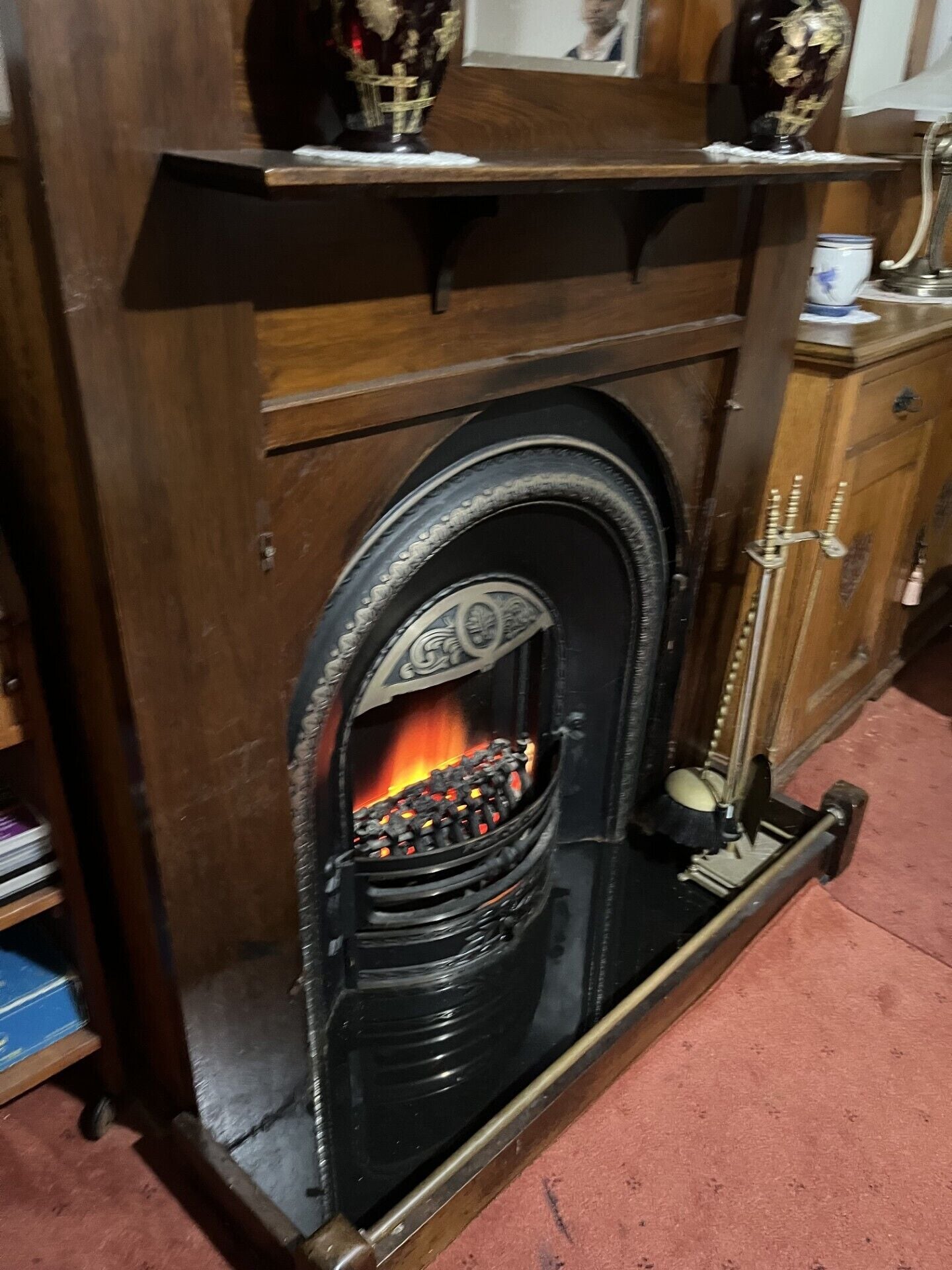 A traditional fireplace with a decorative arch and a fire burning inside.