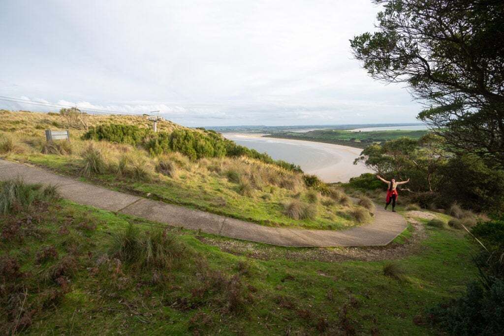 A pathway leading to a beach with a person in a red jacket.