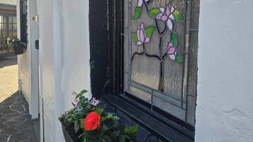 A window with a stained glass design, a black window frame, and a planter with flowers.